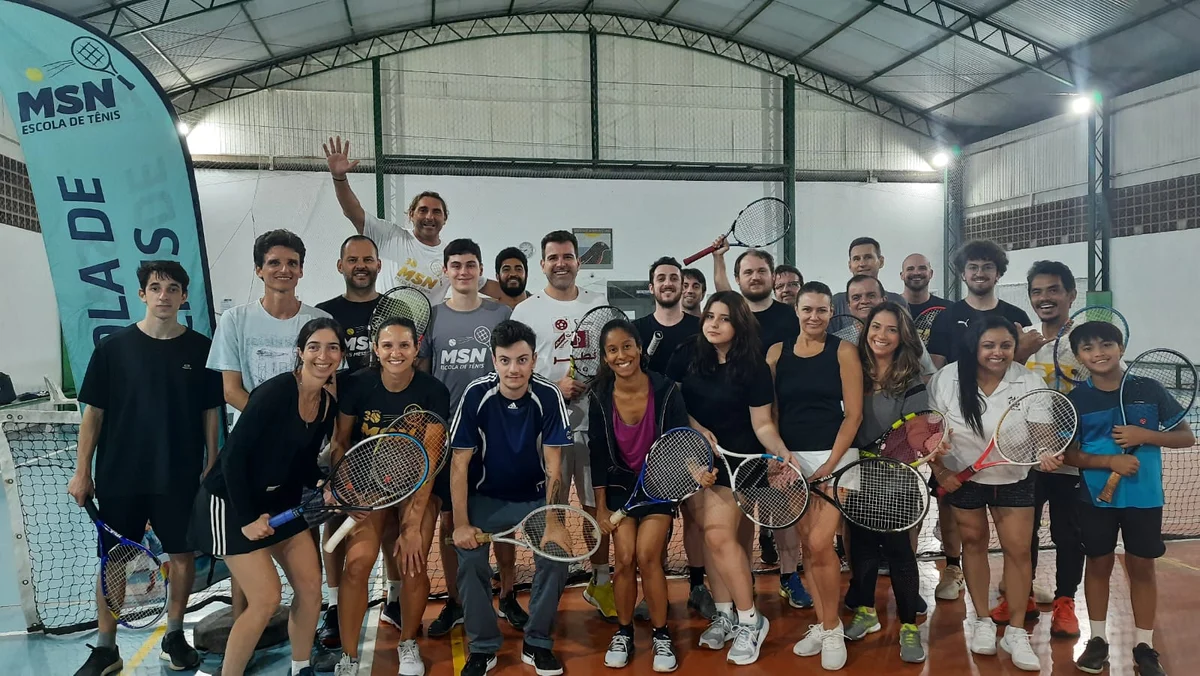 Alunos da comunidade MSN reunidos com raquetes em um encontro de tênis.